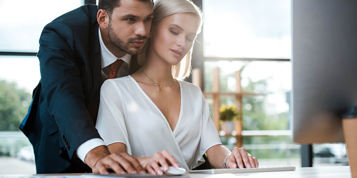 bearded businessman in suit standing near attractive blonde girl in office