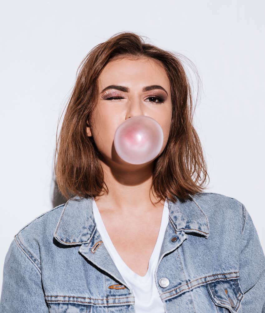 confident woman blows bubble gum and winks