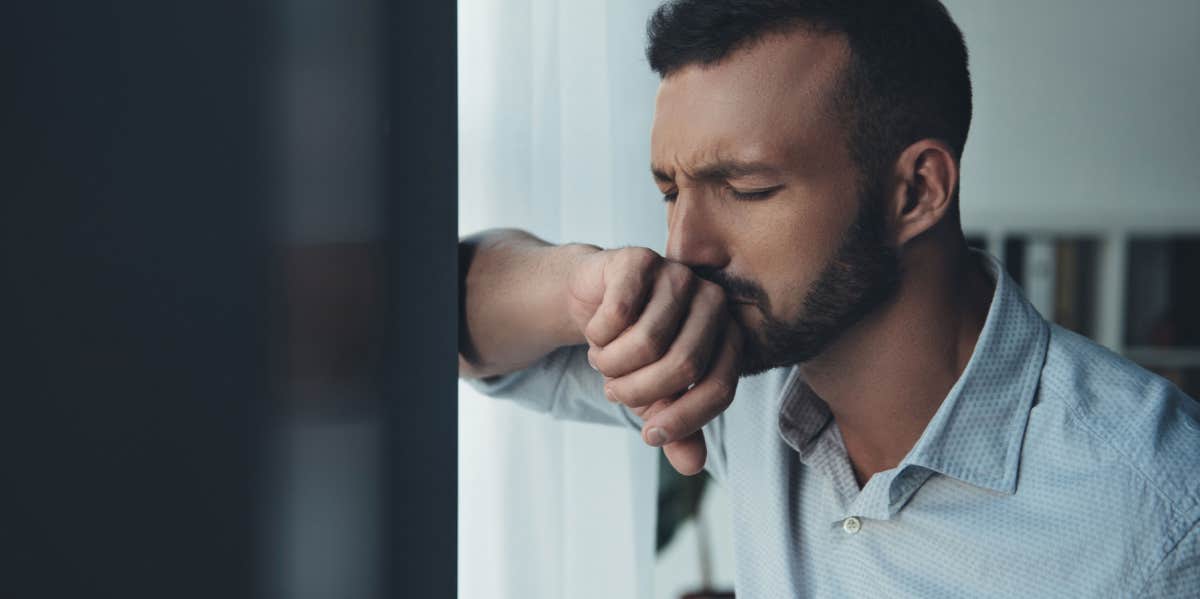 lonely sad handsome man standing near window at home