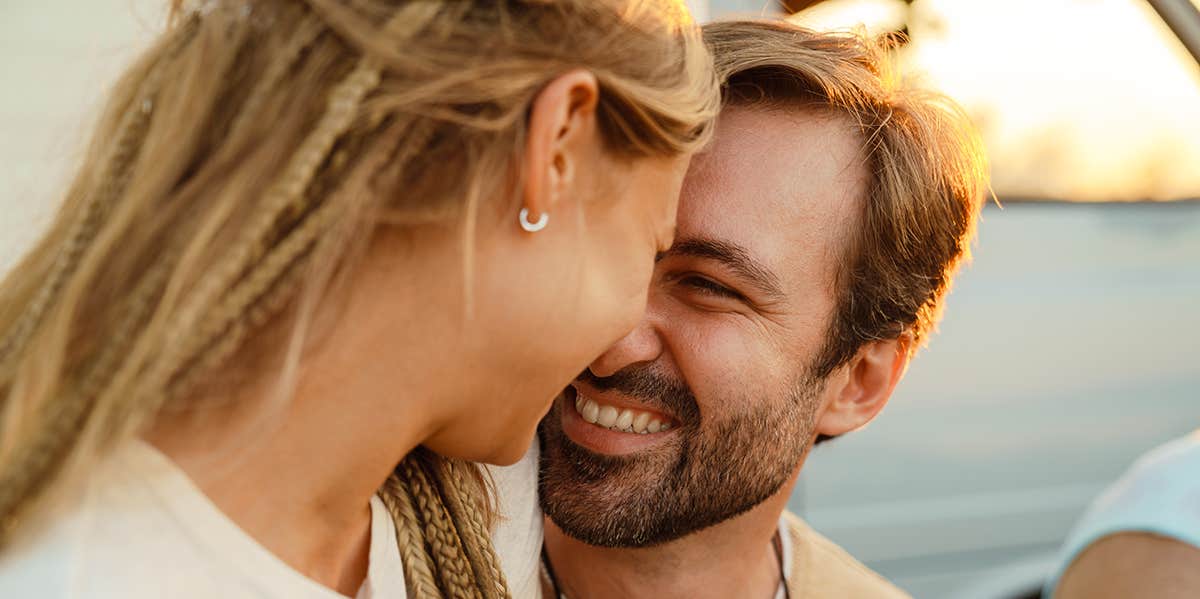 White couple hugging and smiling during picnic with their friends outdoors