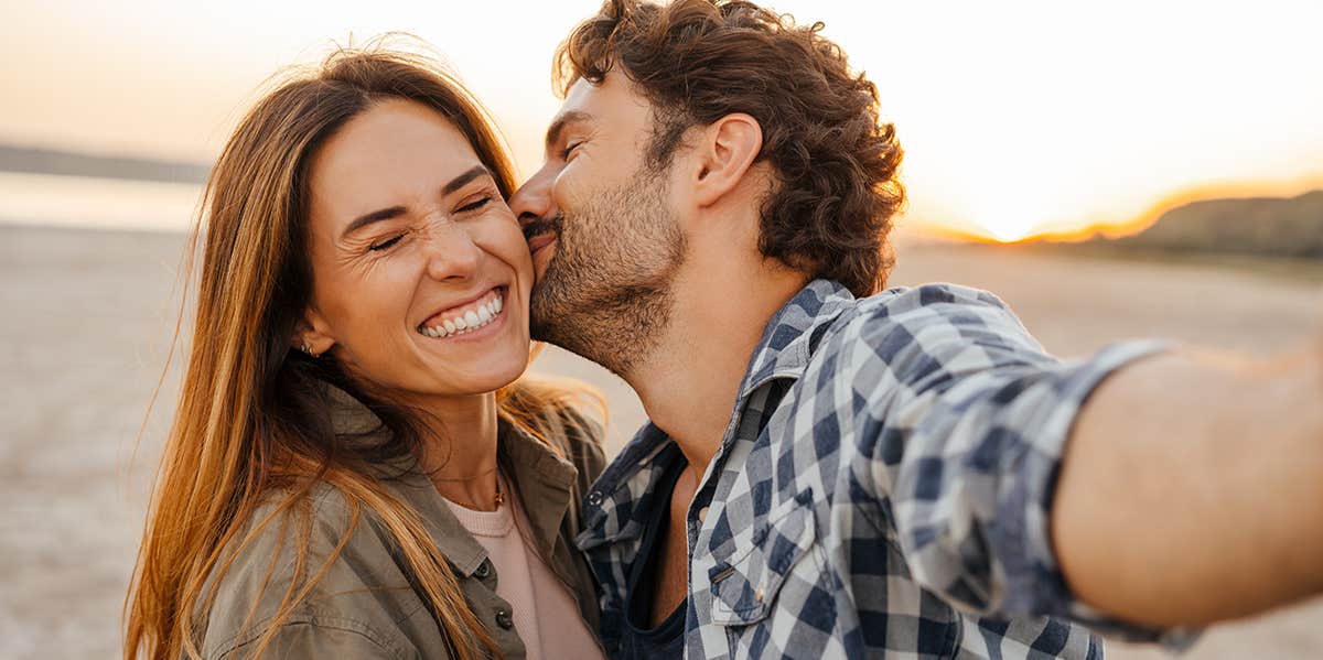 man Kissing woman on cheek at the beach smiling