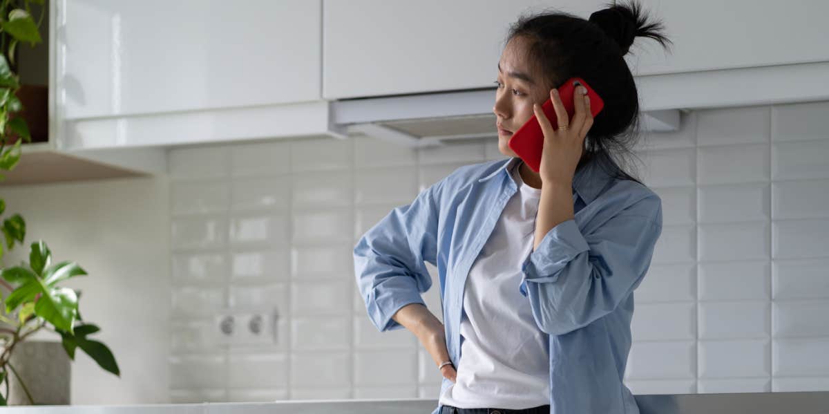 worried woman on phone standing in kitchen
