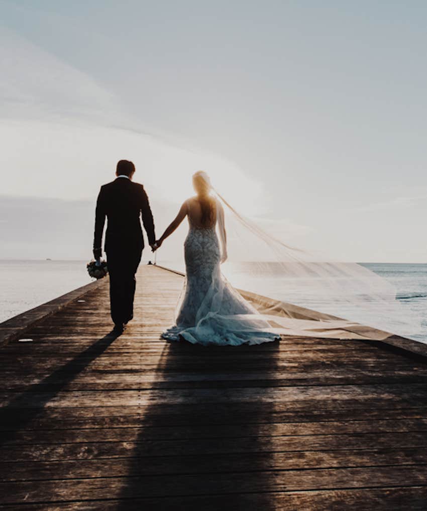 bride and groom at end of pier at sunset