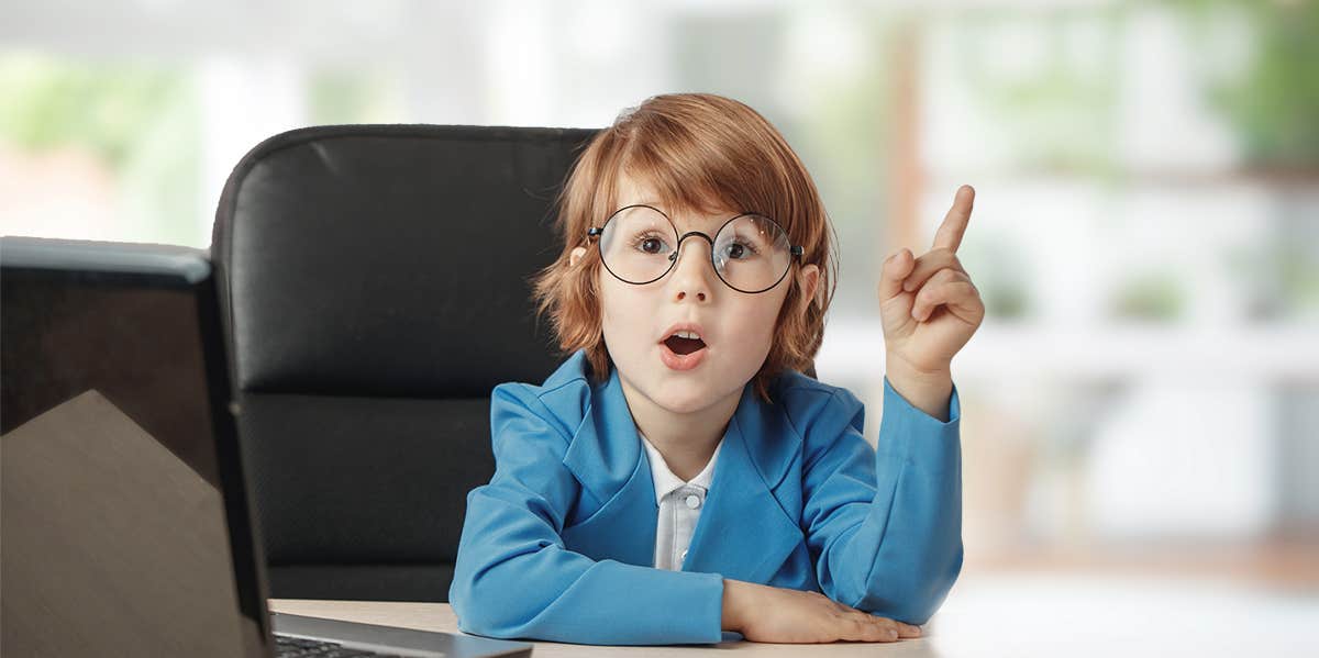 young toddler age boy in suit sitting at a desk