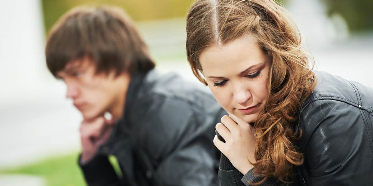 woman sitting on bench with man looking away contemplating sadly