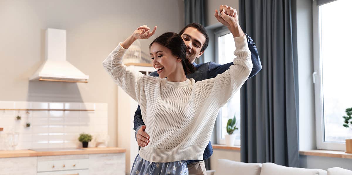 Interracial couple dancing in living room