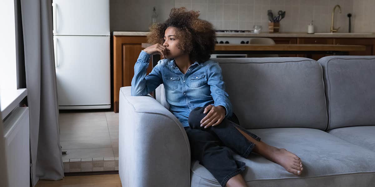 woman of color sitting on couch reflecting