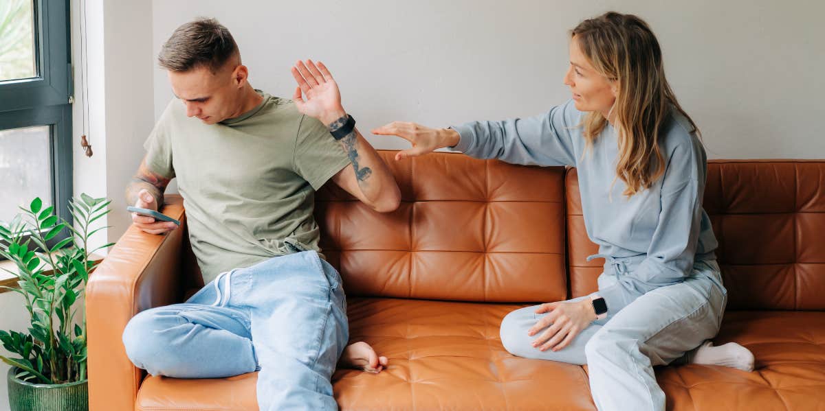 man on his phone with his hand up, ignoring wife