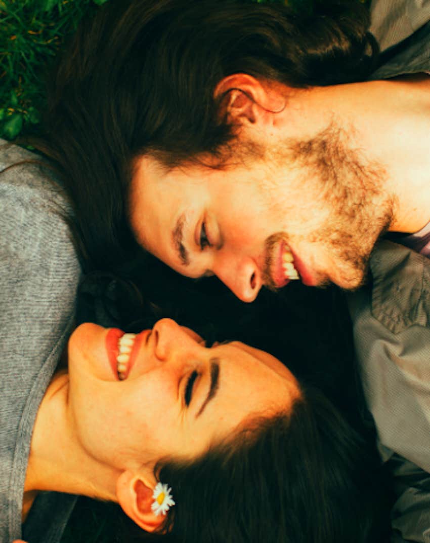 couple laying on grass face to face