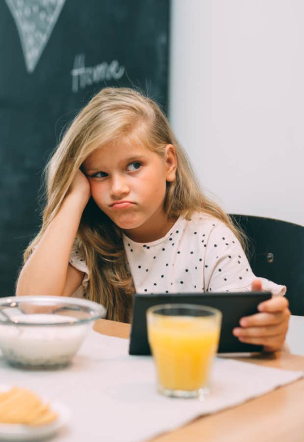 upset young girl sitting at dinner table