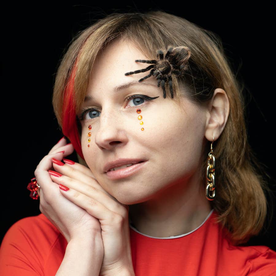 woman posing with tarantula on her face