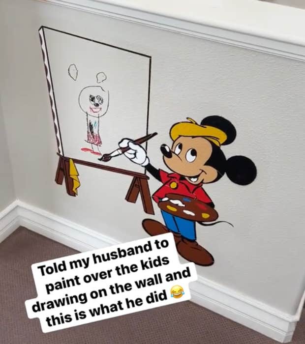 instead of painting over child's drawing on the wall, dad showcases it with mickey mouse painting on an easel