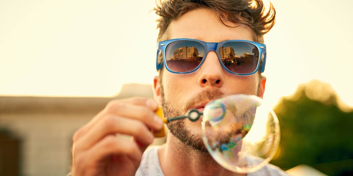 man blowing bubbles towards camera