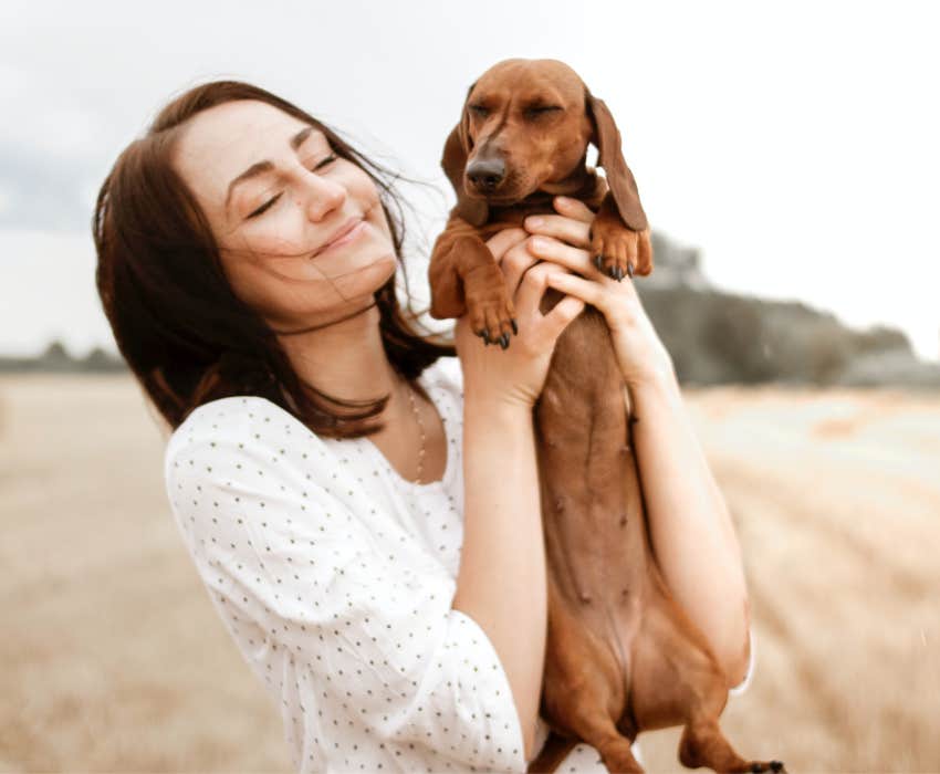 woman holding up a dachsund