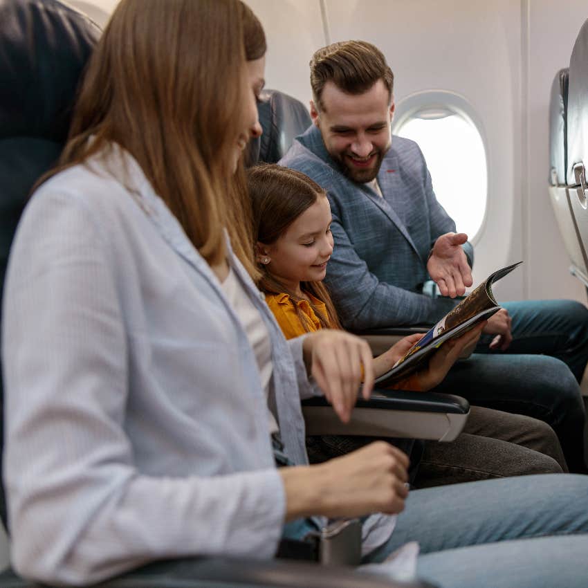 plane passenger using his hands to block the screen of the person sitting behind him