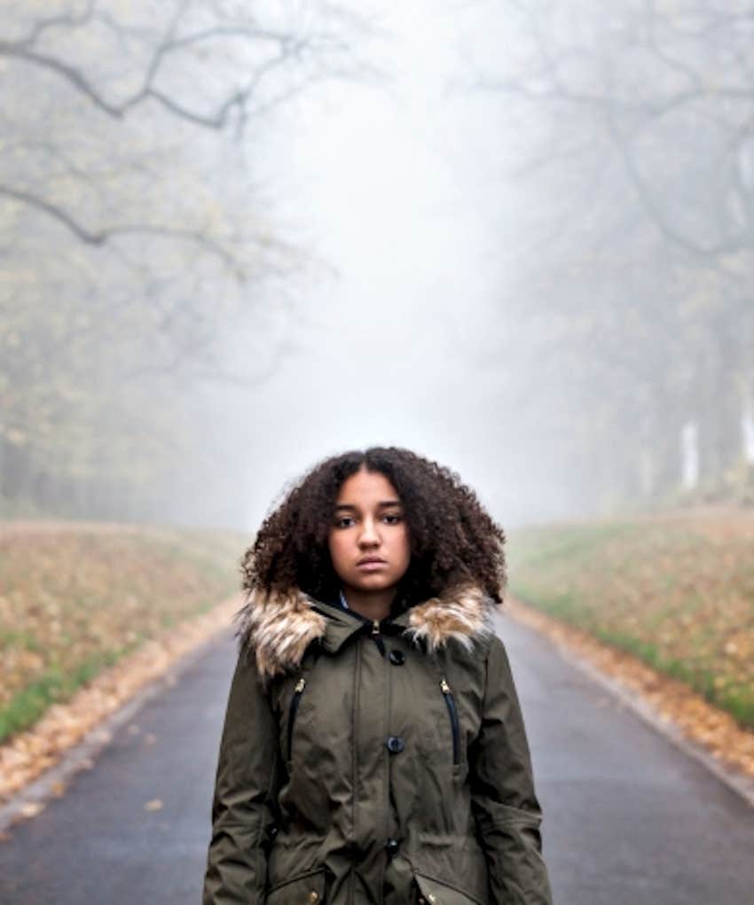 emotionally blank woman stands in middle of empty road, it is autumn time