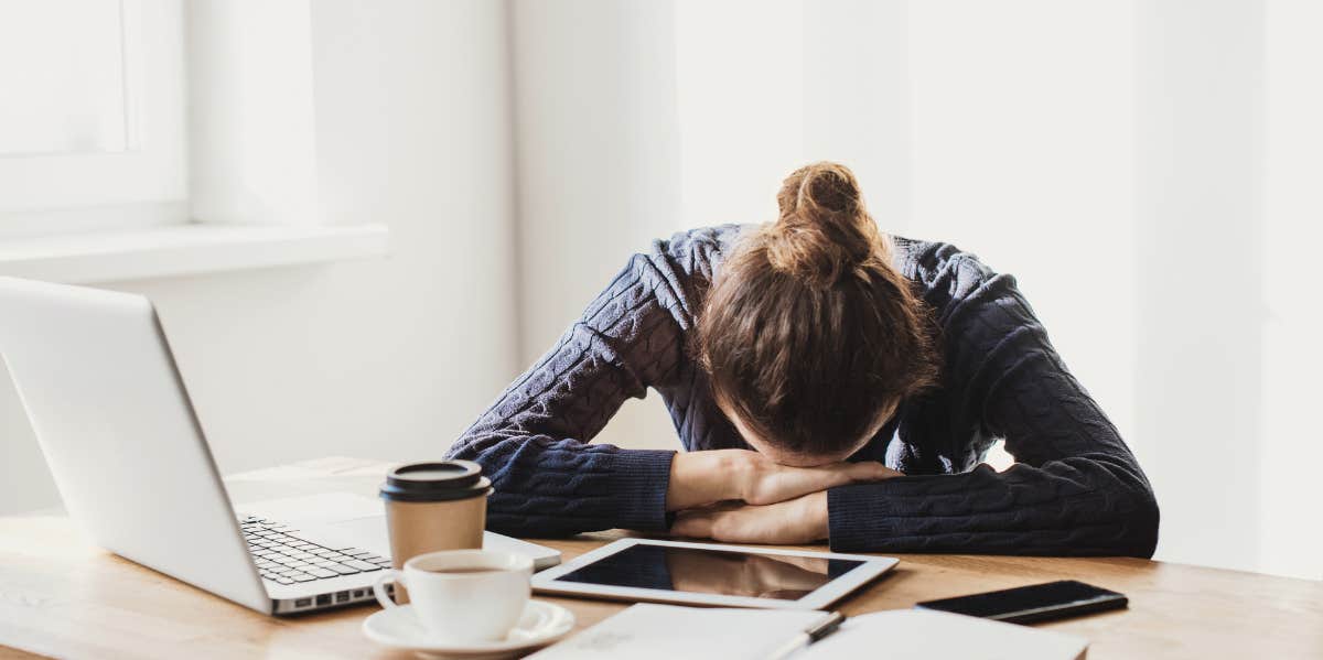 If These 5 Signs Sound Familiar, You're Secretly Struggling With High-Functioning Anxiety Overwhelmed woman with head on desk