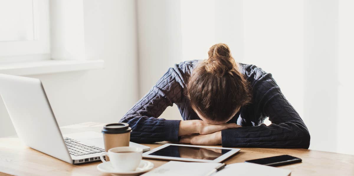 Overwhelmed woman with head on desk