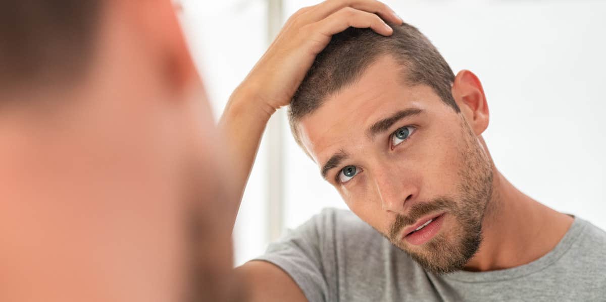 man with his hands on his head looking in a mirror