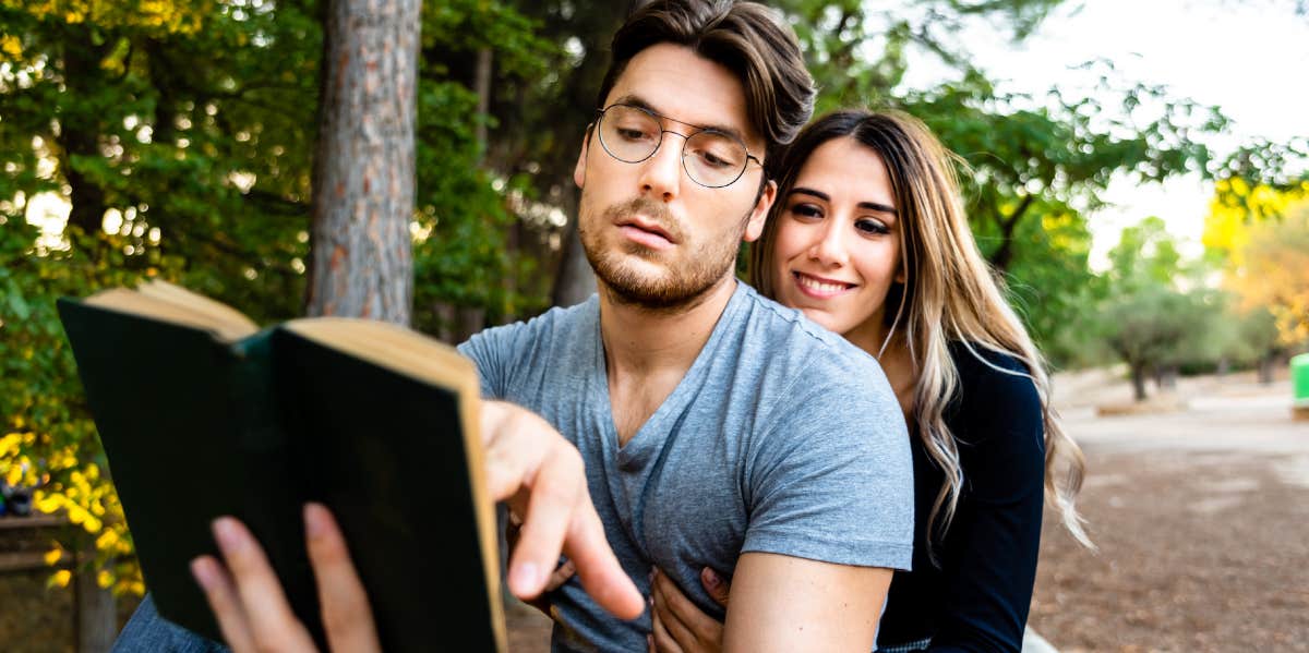 man reading a book his partner wanted him to and showing interest