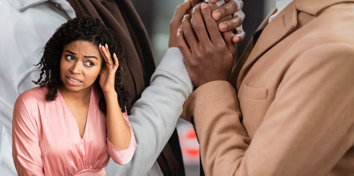 woman with a shocked expression as her friend and his partner grasp each others hands in anticipation