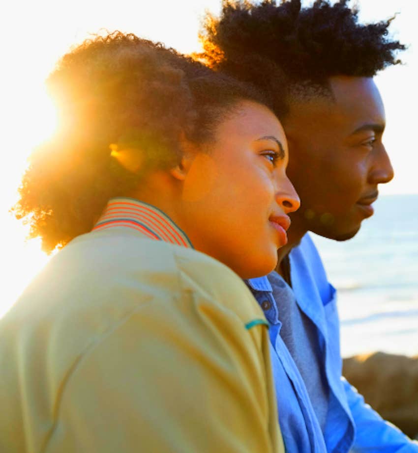 couple sit closely at sunset