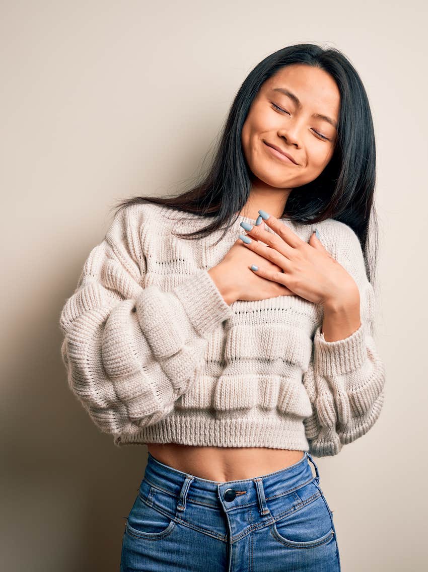 happy woman holds hands over heart