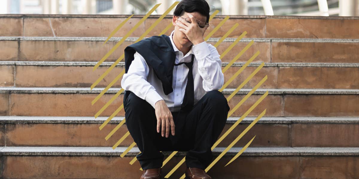 unemployed man, sitting on tsteps outside with his hands rubbing his eyes