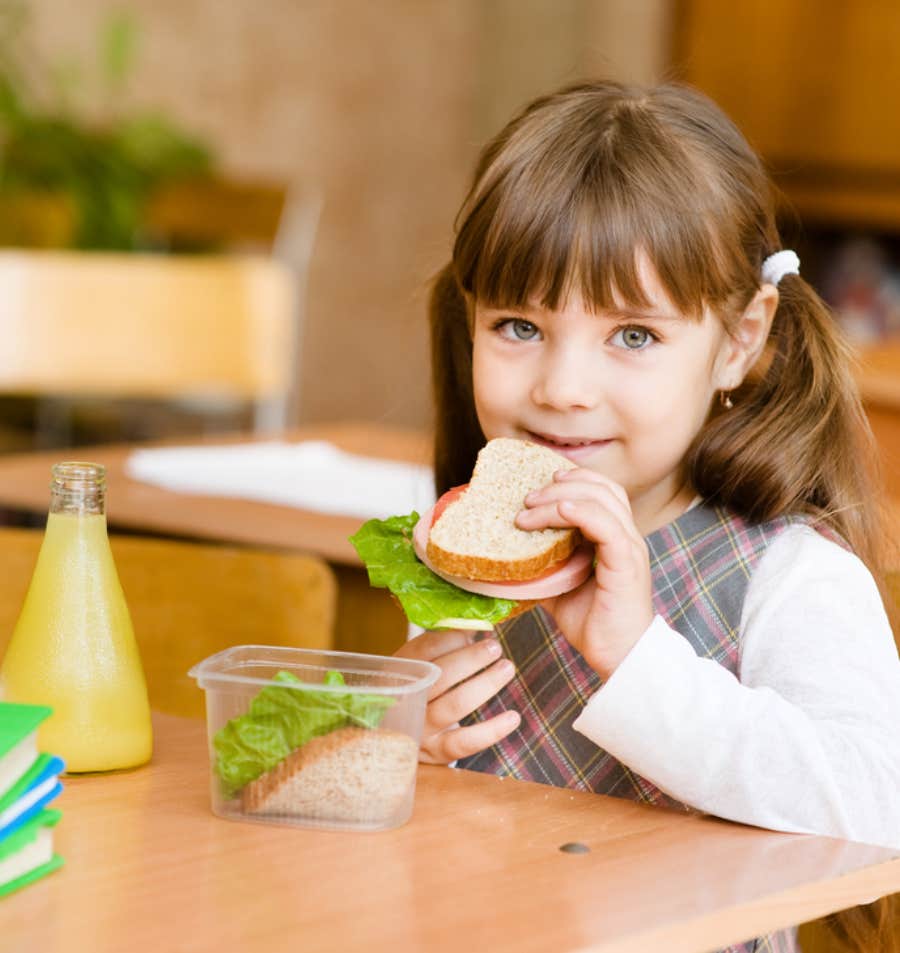 young girl eating a sandwich at school