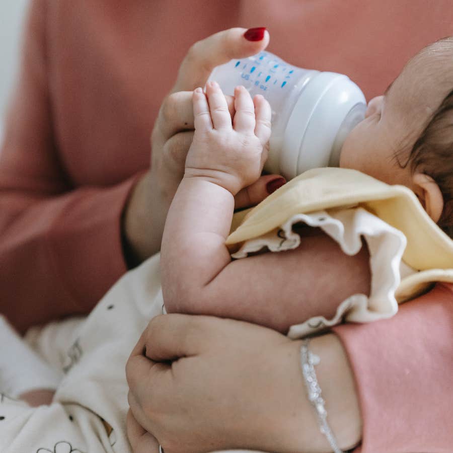person feeding infant with a bottle