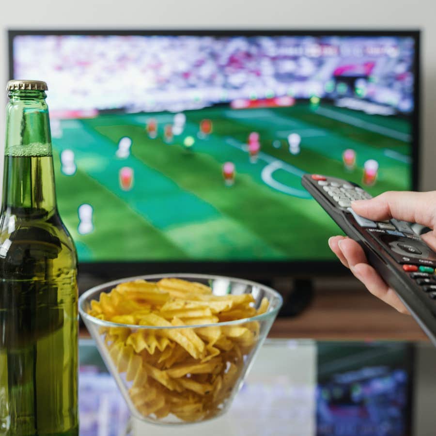 person using a tv remote with sports on