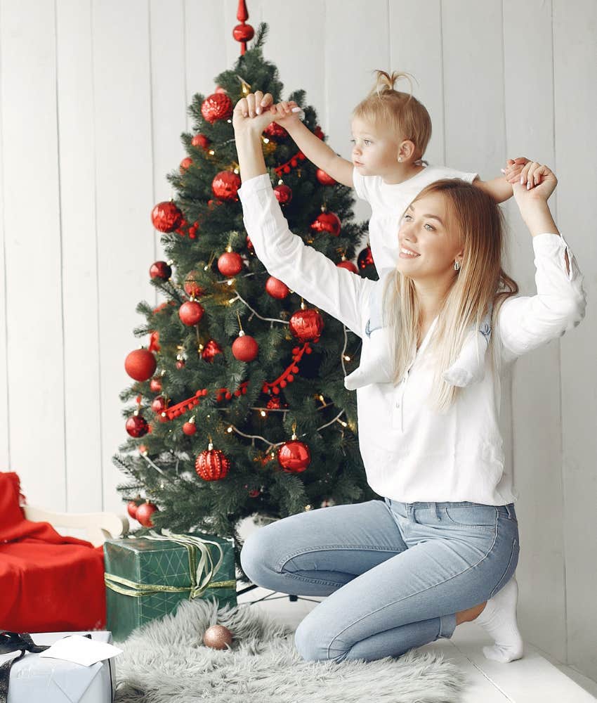 woman playing with young daughter next to christmas tree