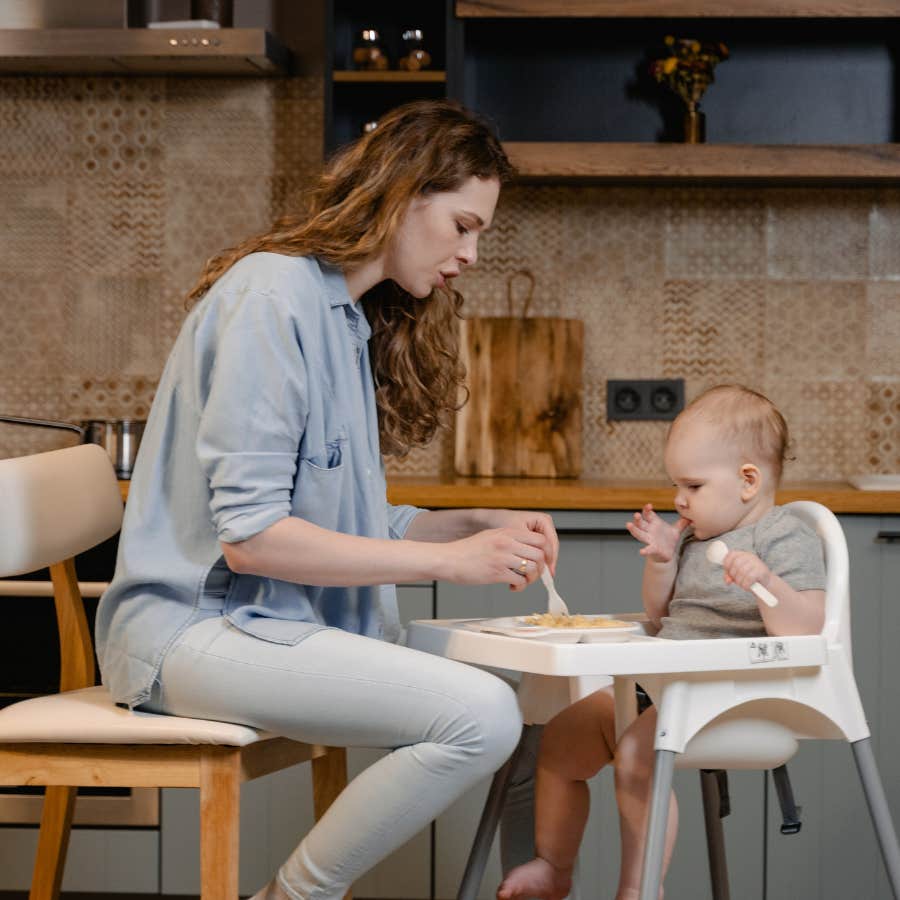 woman feeding infant in high chair