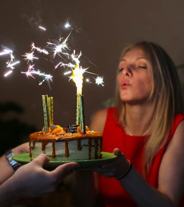 woman blowing out sparkling candles on cake