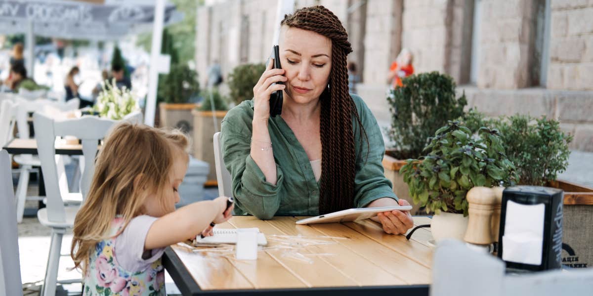 Being An iPhone Addict Makes Me A Better Mom mom on phone while at lunch with her child