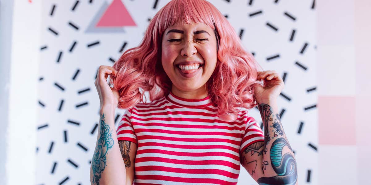 Woman with tattoos, pink hair and smile on her face