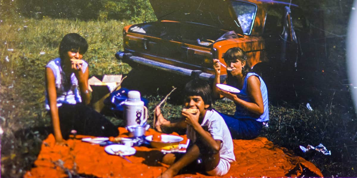 CIRCA 1983: Vintage photo of family car trip vacation picnic scene