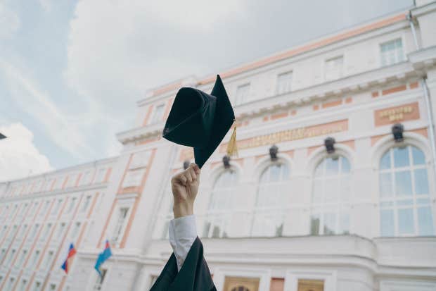 person holding graduation cap in the air