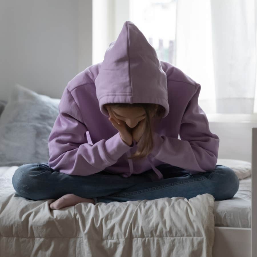 dejected teenager sitting on her bed