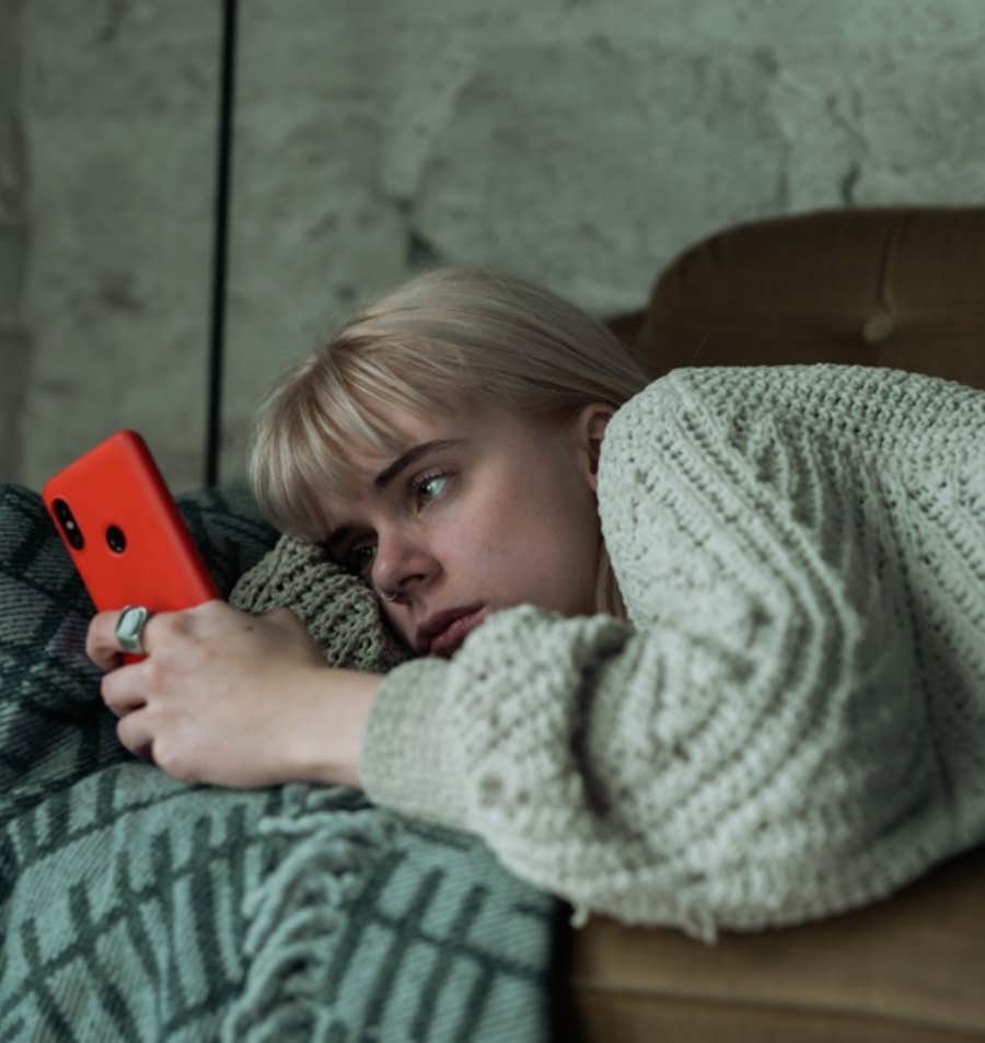 woman laying down looking at phone