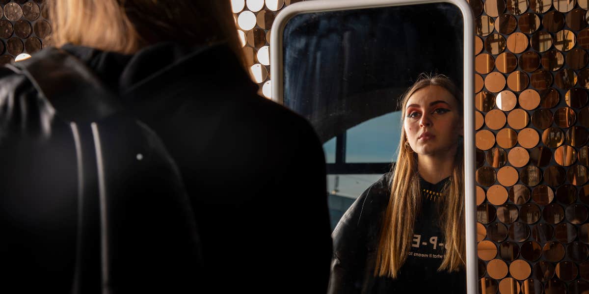 Signs You Don't Feel Emotionally Safe In Your Relationship girl looks at herself in the mirror