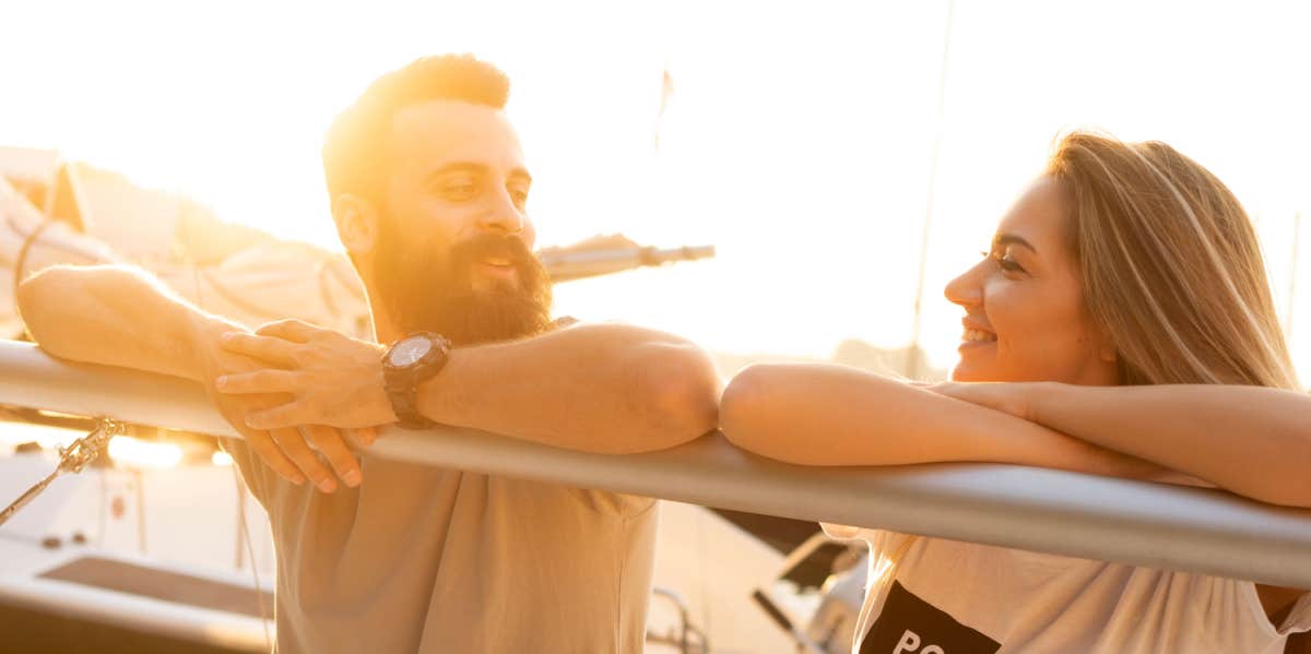 man and woman hanging out over boat rail-touching elbows