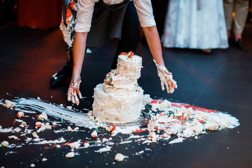 man picking smashed wedding cake off of floor