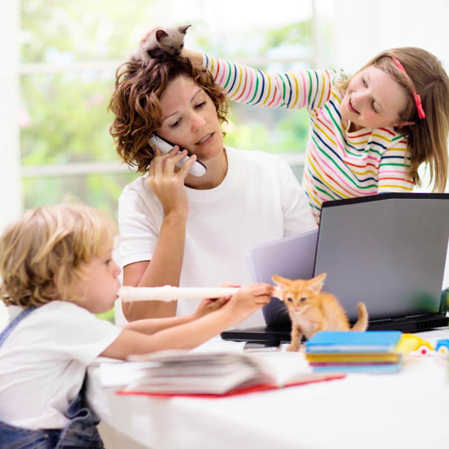 girl playing with mom&#039;s hair while she&#039;s on the phone and working