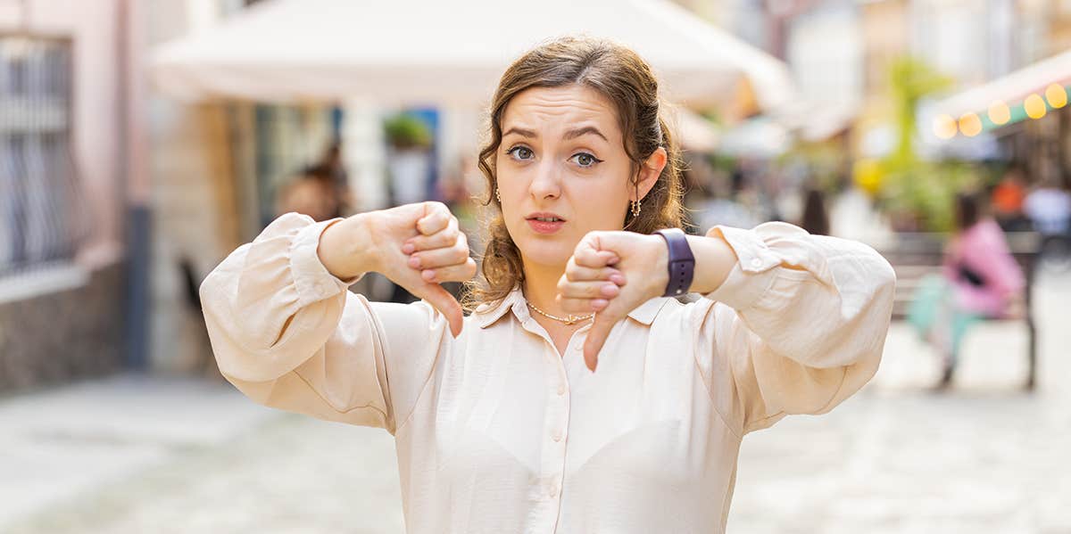 4 Questions You Should Never Ask In A Relationship (If You Want It To Last) woman standing in street giving thumbs down