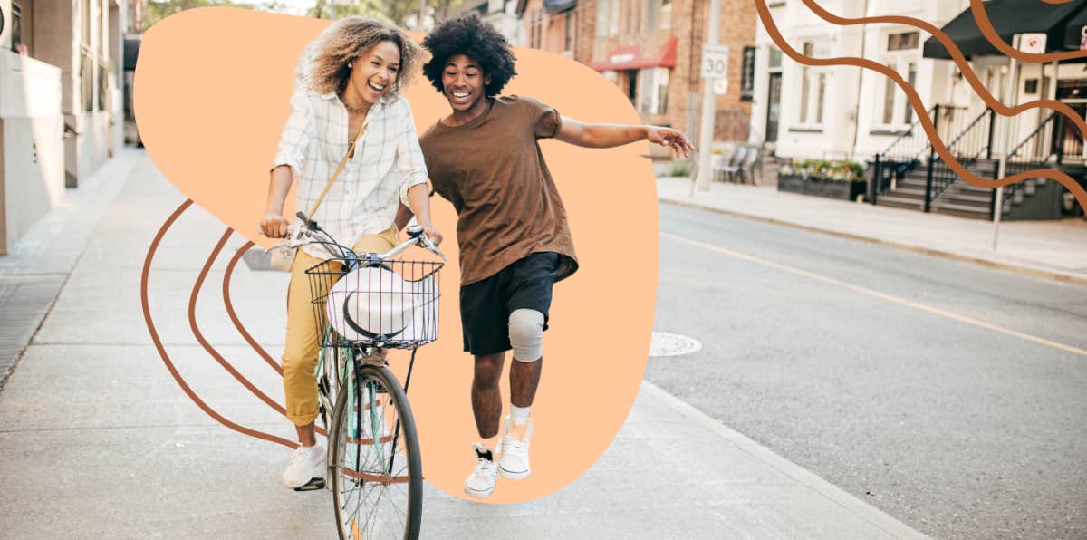 Woman riding a bike while man behind her cheers