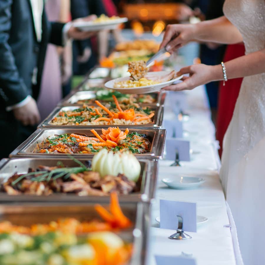 bride getting food at wedding buffet