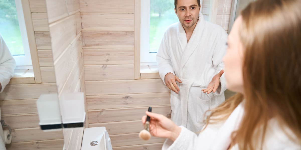 man in bathroom with frugal wife defending his toilet paper usage 