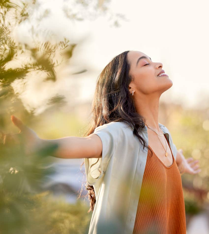 woman with arms outstretched breathing in fresh air