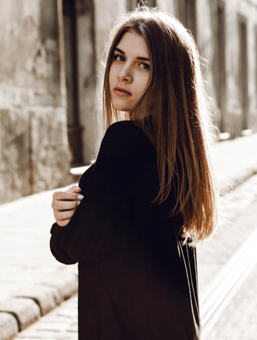 woman on an empty street turns to face you